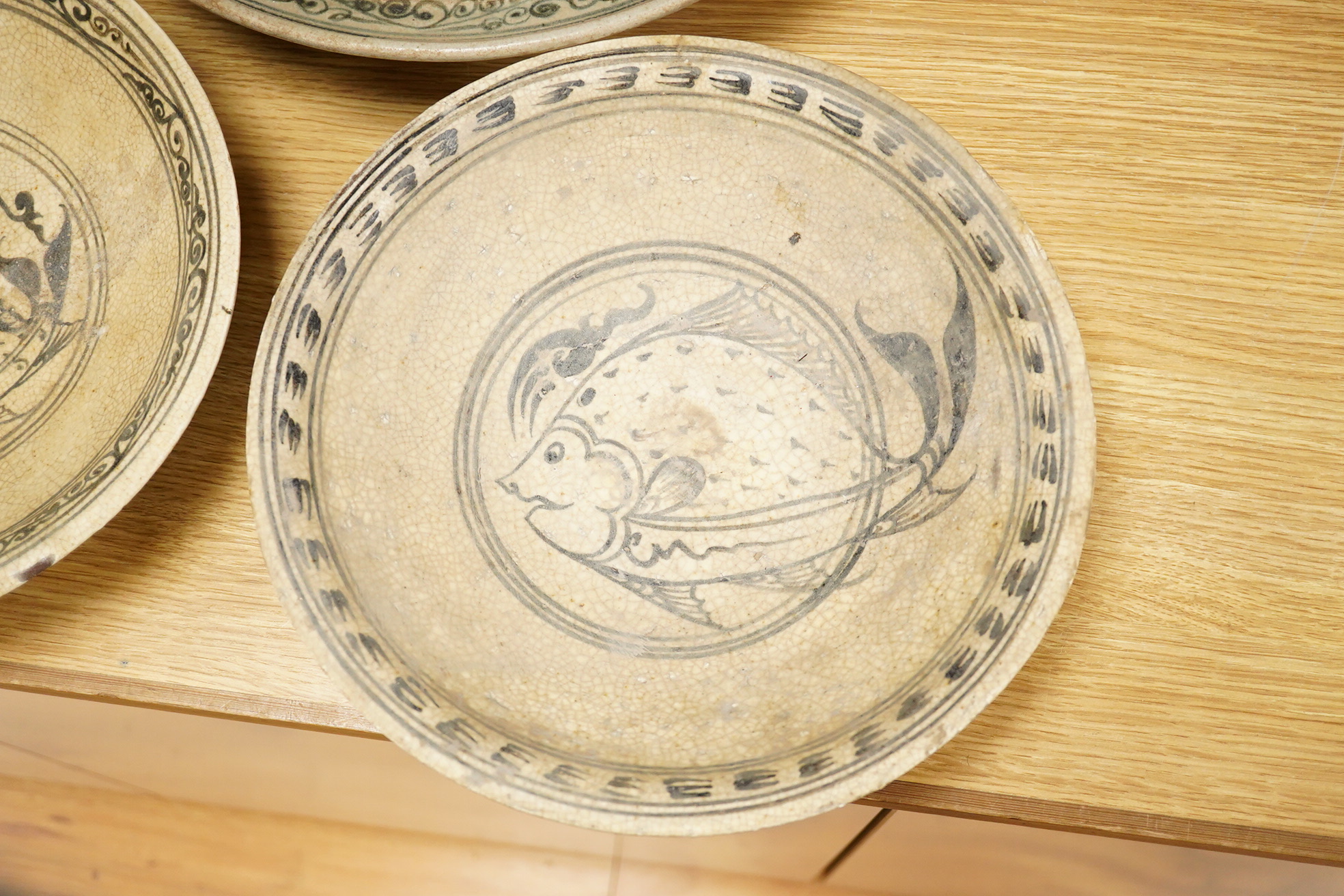 A group of three Thai underglaze blue or black crackle glaze dishes, two decorated with fish, largest 38cm in diameter